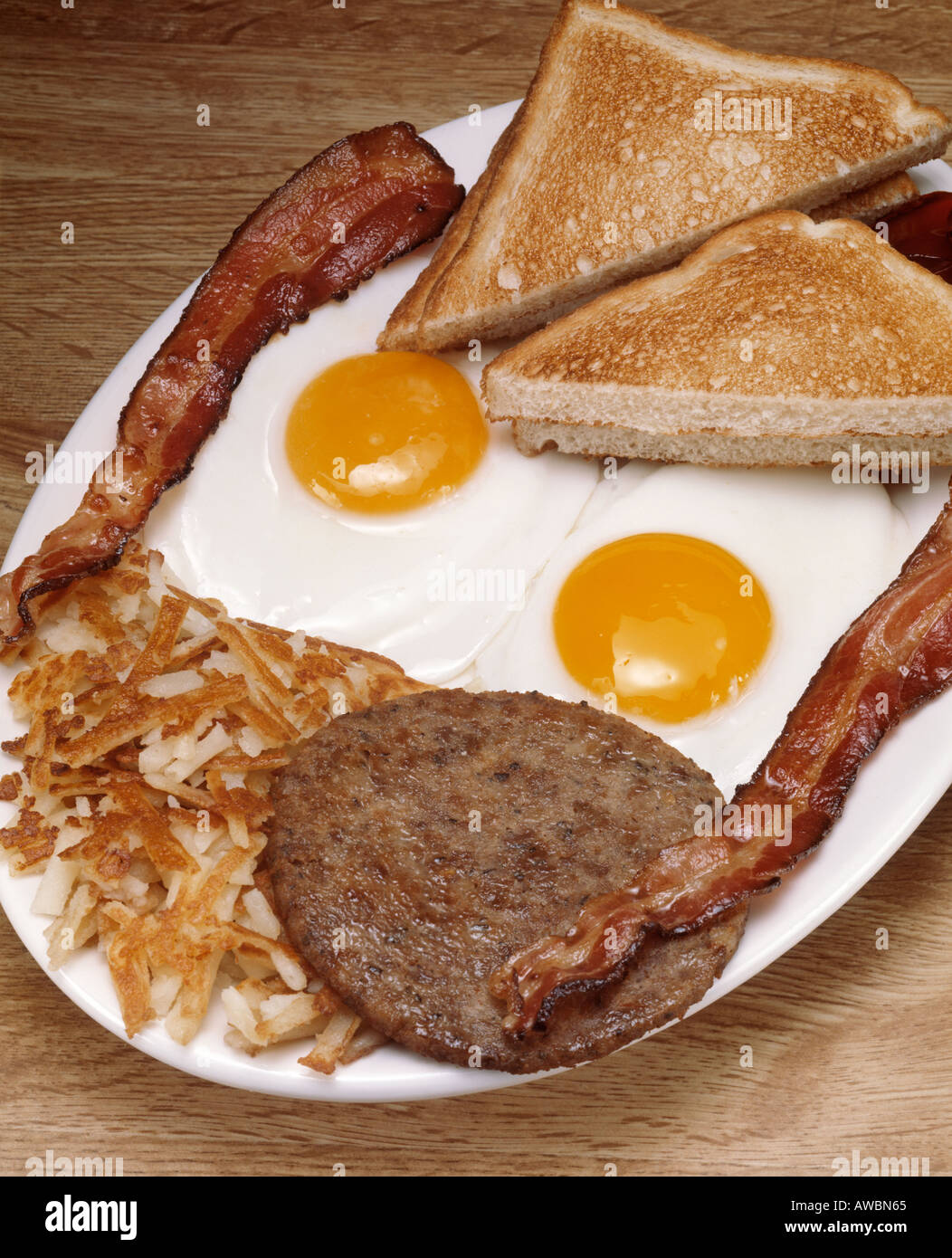 hearty breakfast plate two fried eggs sunny side up bacon strips Stock