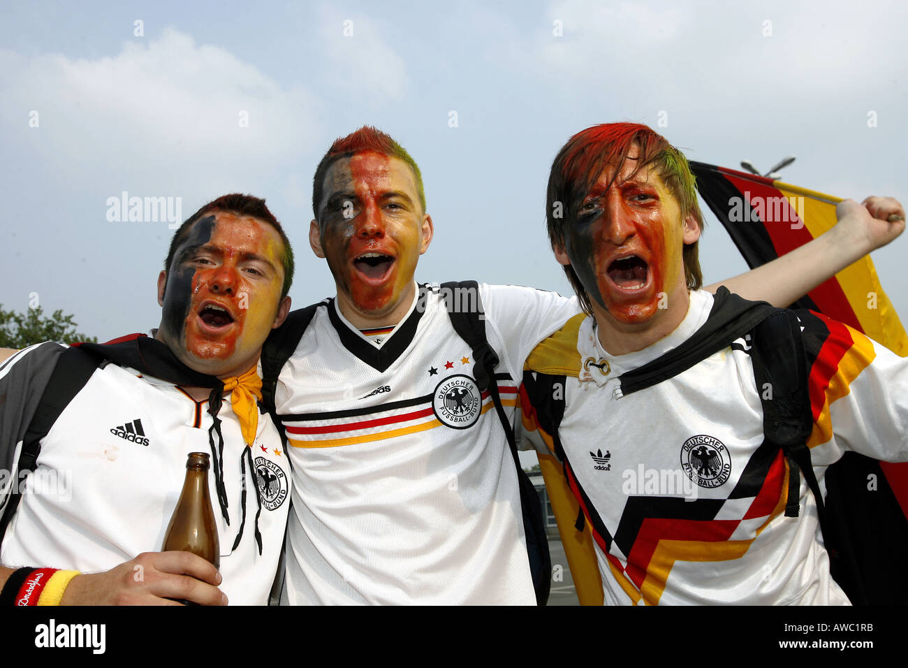 Three male German supporters with painted faces sing in the streets during the 2006 World Cup Stock Photo