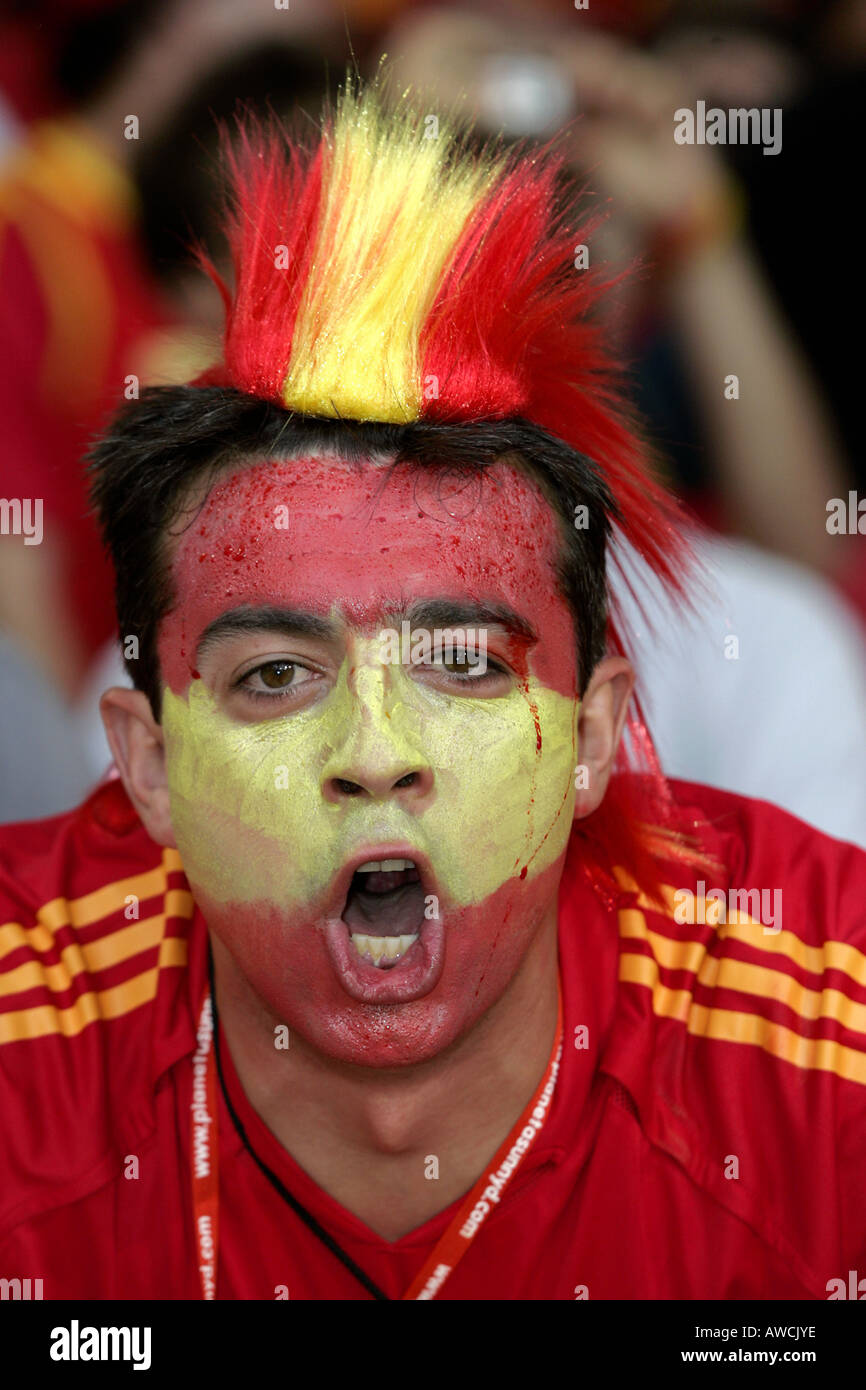 A male Spanish fan wearing face paint and a wig singing in the crowd during the 2006 World Cup Stock Photo