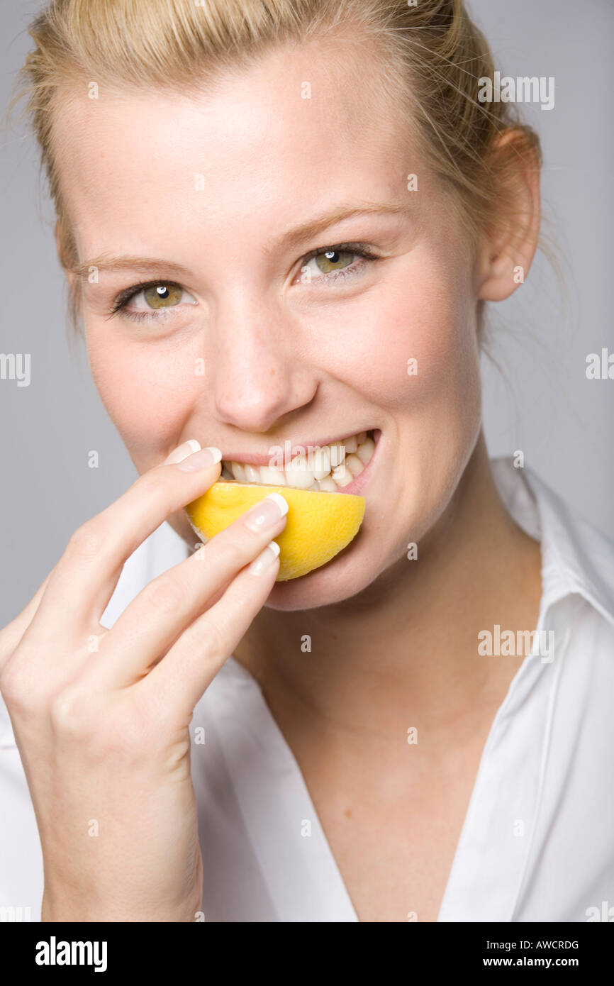 Young woman biting into a lemon Stock Photo