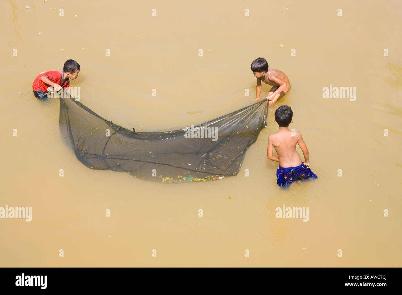 Three Cambodian boys casting a fishing net, Cambodia, Southeast Asia Stock Photo