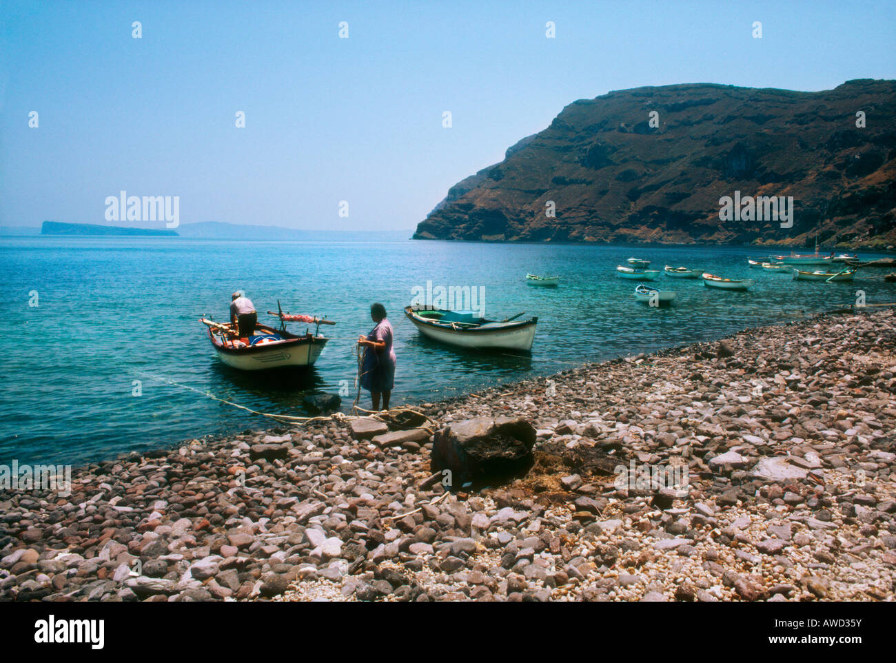Wife helping her husband bring the fishing nets off the boat to bring ashore, Santorini Greek Islands Stock Photo