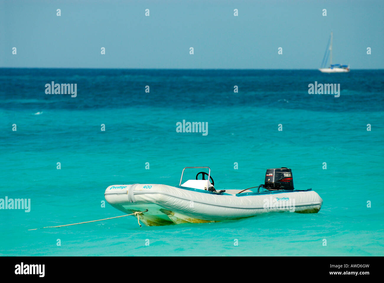 Turquoise waters, ubber dinghy in the sea with sailboat in the background, Cayo Largo, Cuba, Americas Stock Photo