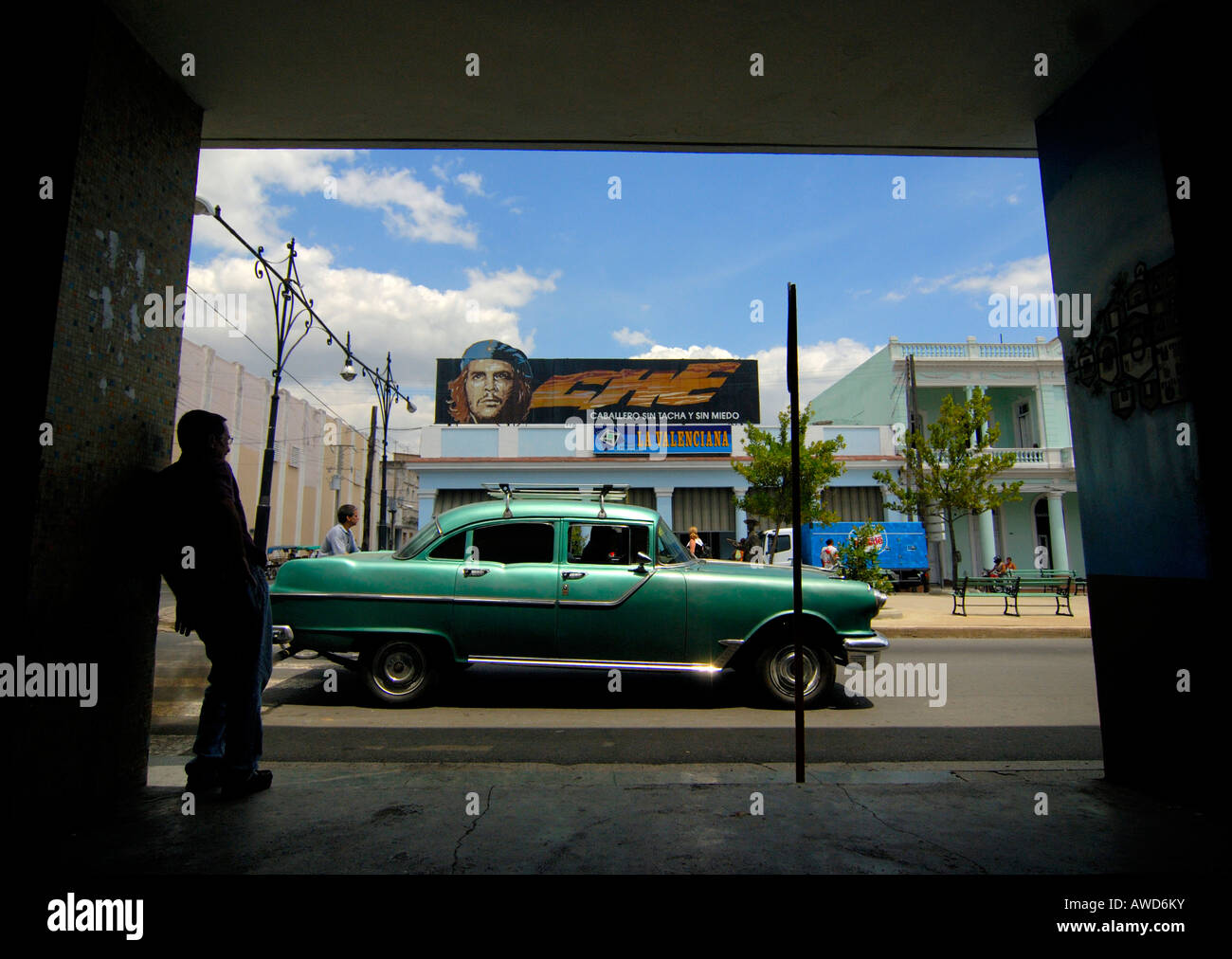 Green vintage car parked in front of political propaganda featuring Che Guevara in Cienfuegos, Cuba, Caribbean, Americas Stock Photo