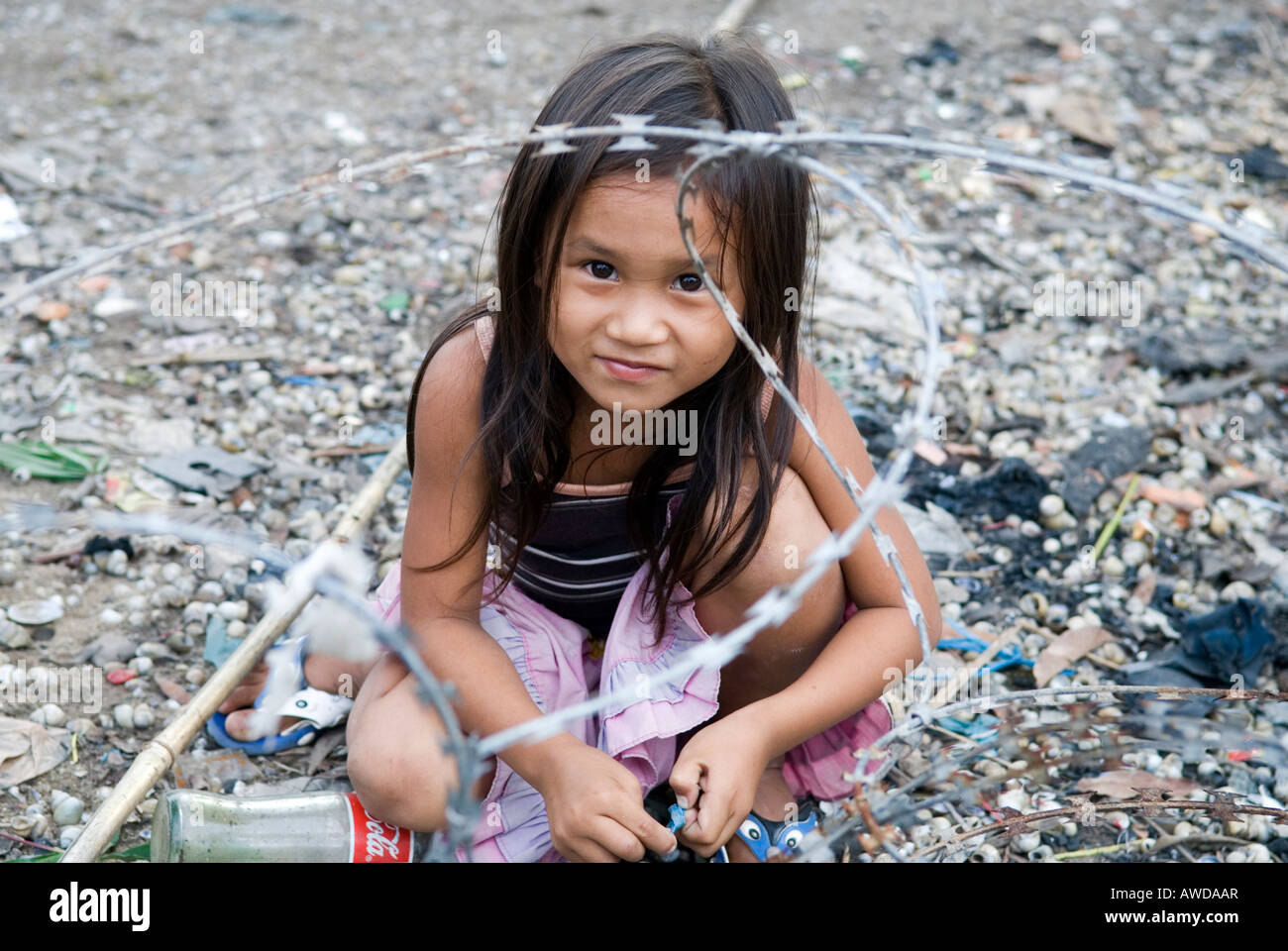 Girl playing between barbed wire in a slum. The inhabitants are being threatened by forced resettlement, Dey Krahom slum area,  Stock Photo