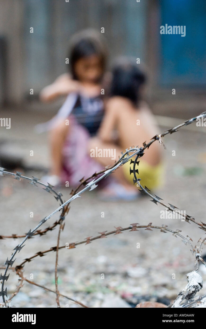 Children playing behind barbed wire in a slum. The inhabitants are being threatened by forced resettlement, Dey Krahom slum are Stock Photo