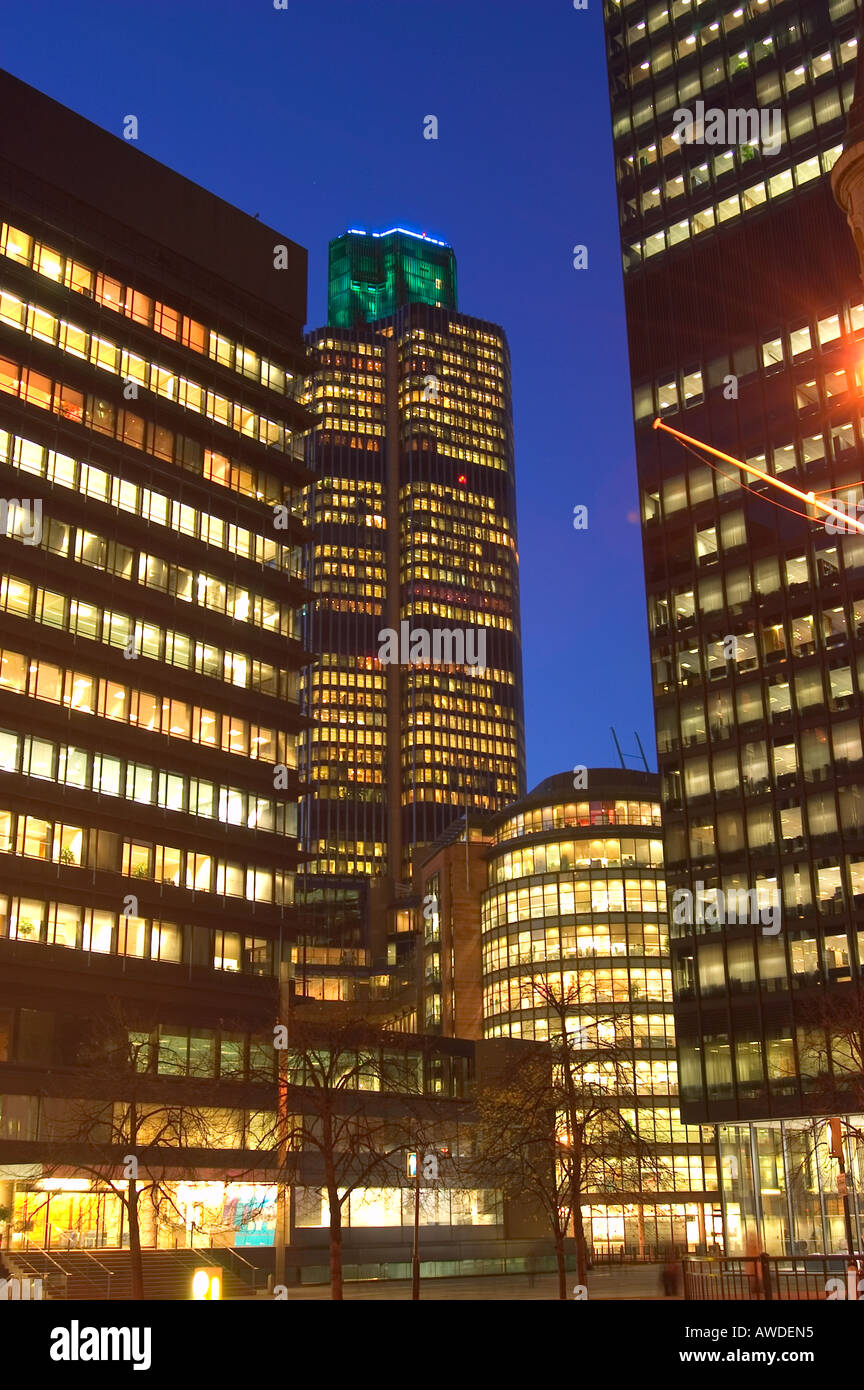 Tower 42 in the city of London, lit up at Nightime, sandwiched between other buildings Stock Photo