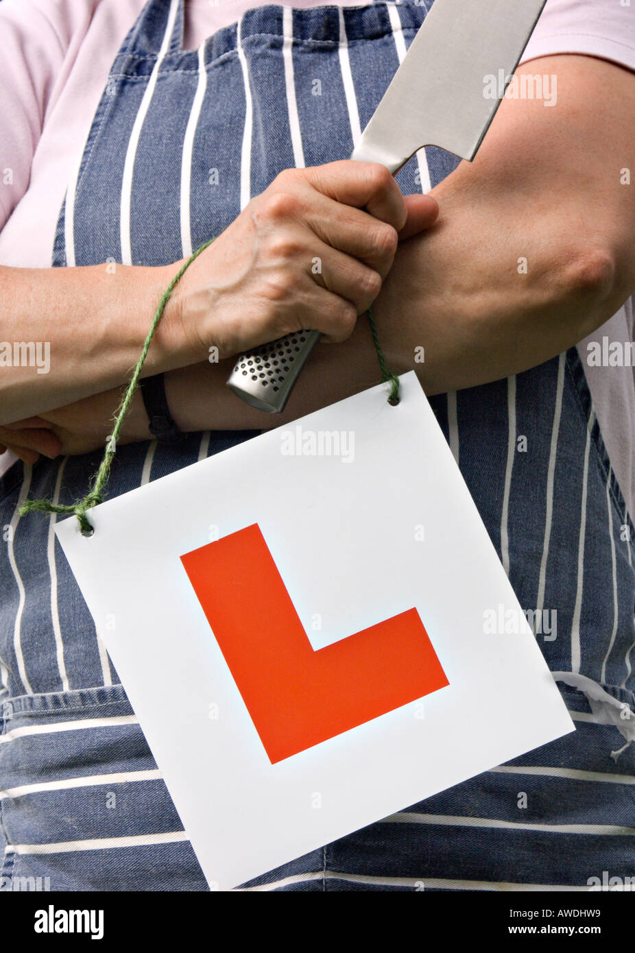 Learner chef holding knife wearing L plate Stock Photo