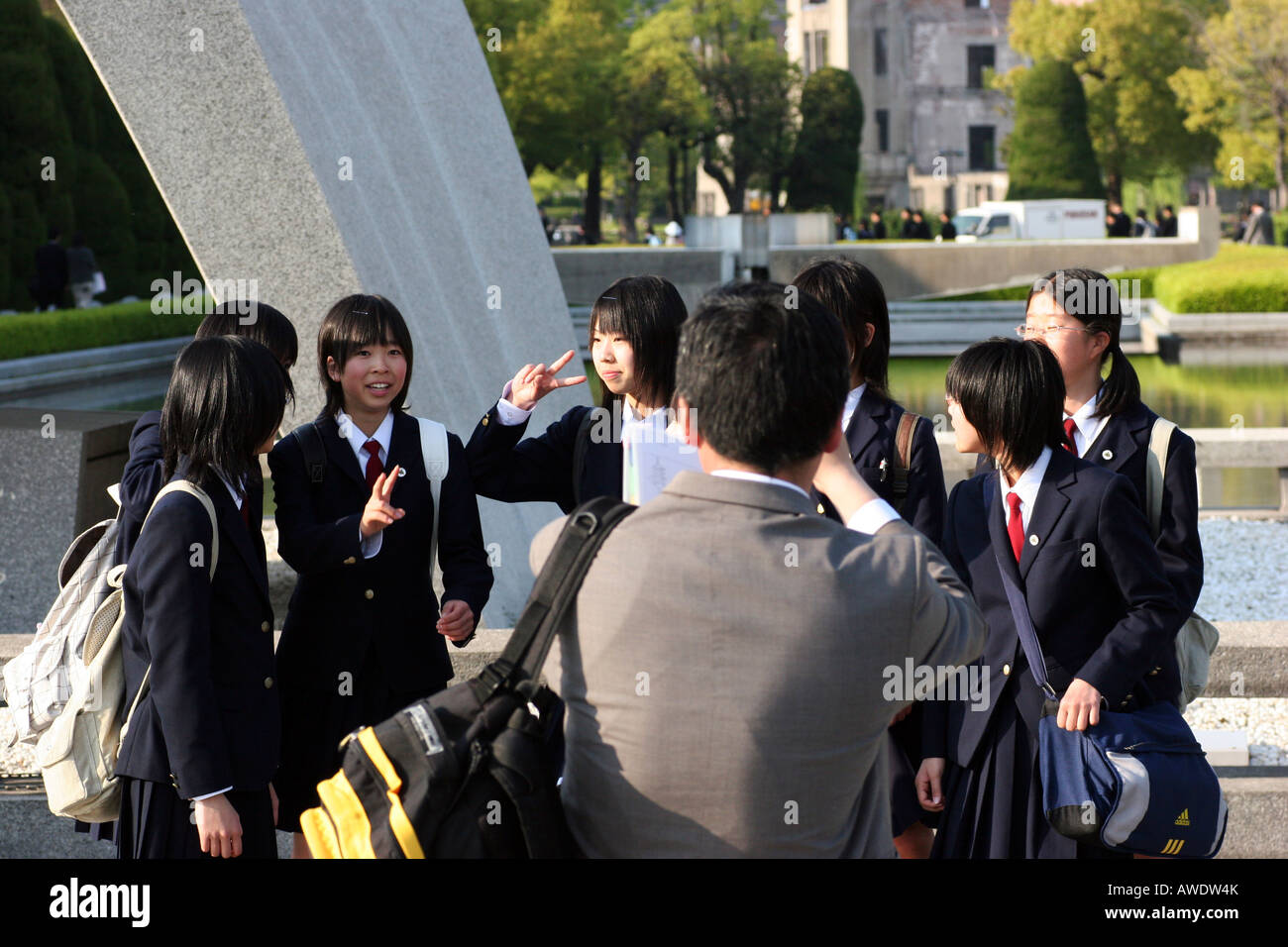Teacher is taking pictures of group of Japanese school children posing in front of the Cenotaph in Hiroshima, Japan. Stock Photo