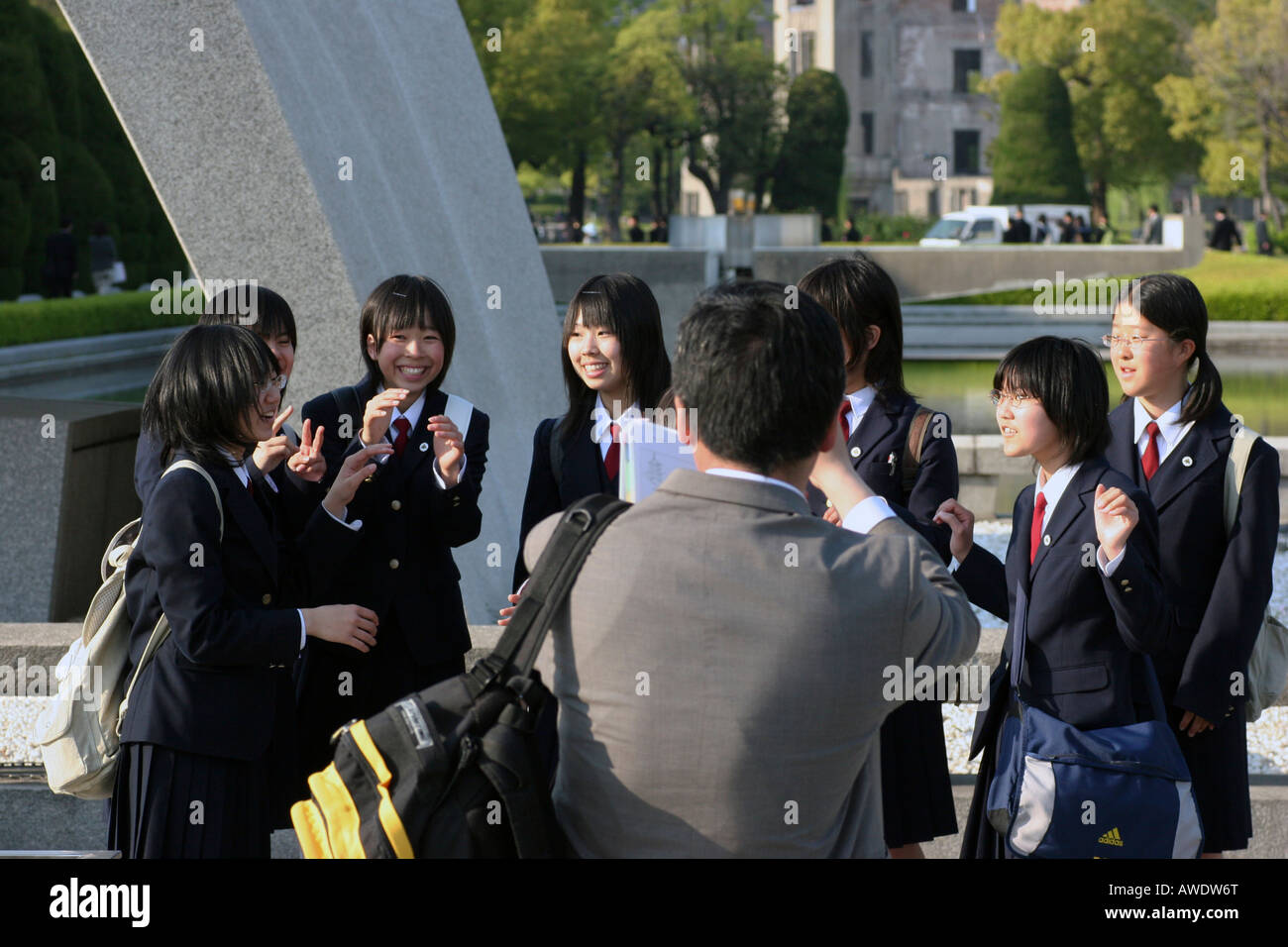 Teacher is taking pictures of group of Japanese school children posing in front of the Cenotaph in Hiroshima, Japan. Stock Photo