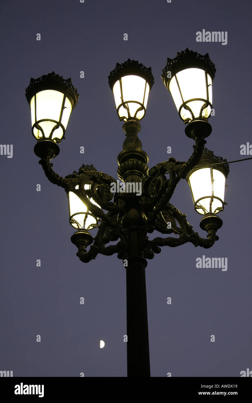 Portrait view of a cluster of 5 street lights upon one pole shining in the  night with the moon low in the background Stock Photo - Alamy