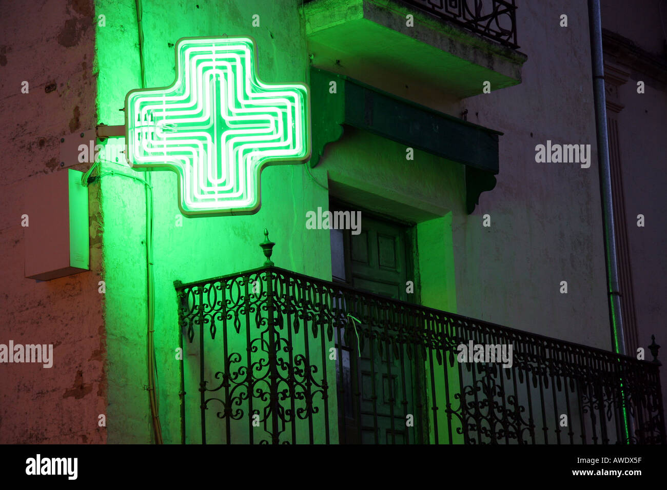 A spanish pharmacy sign glows in the night Stock Photo