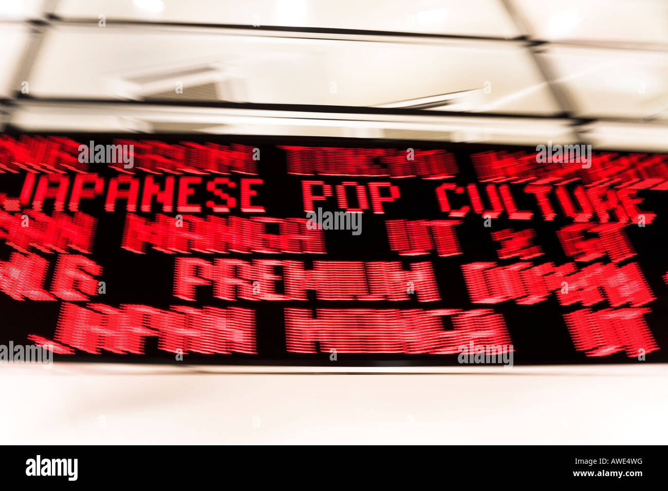 Scrolling digital neon sign in Tokyo street at night. Motion blur on pan as camera follows the phrase JAPANESE POP CULTURE. Stock Photo