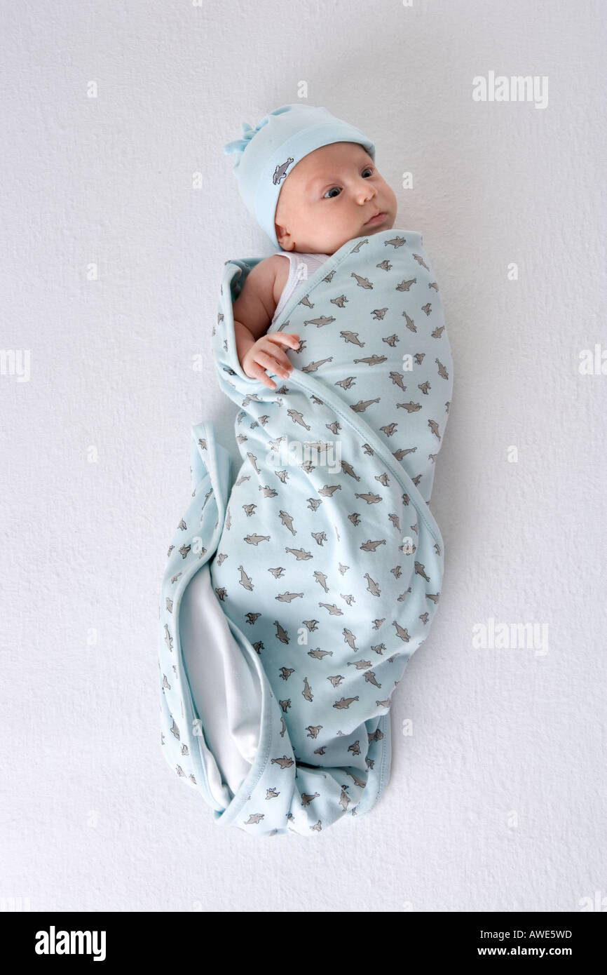 Baby wrapped in a towel lying on the floor Stock Photo