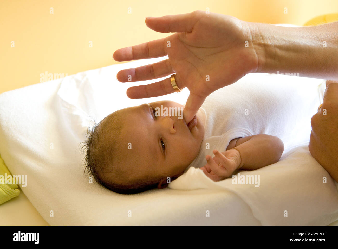 Baby is sucking on mothers finger Stock Photo - Alamy