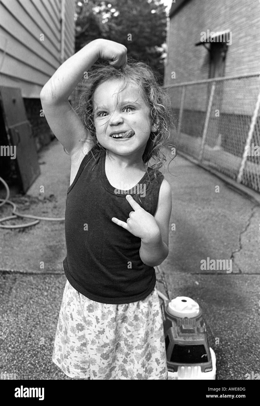 Young girl stikes a silly pose in her driveway in Brooklyn New York Stock Photo