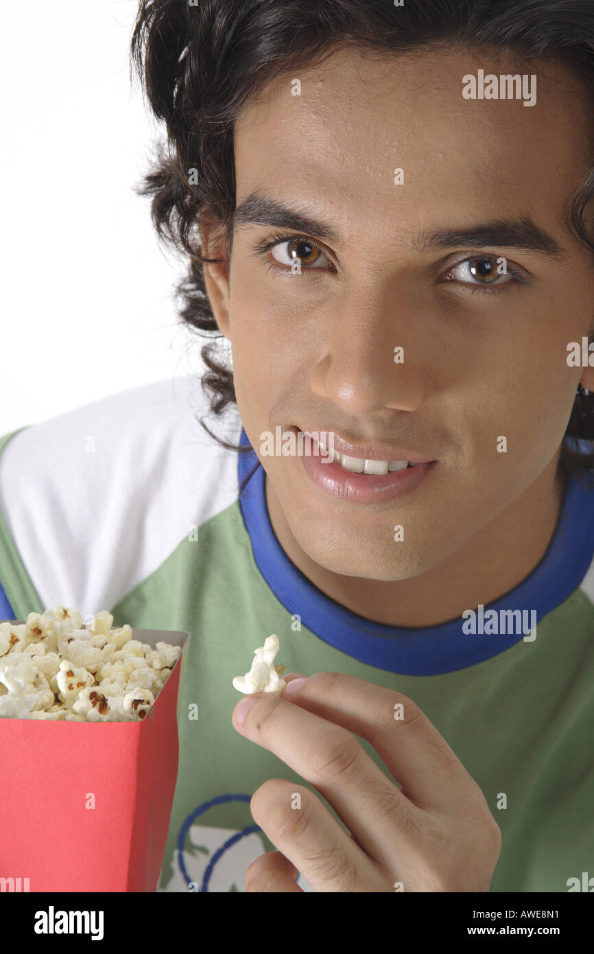 ANG200442 Teenage boy holding popcorn pack in one hand and eating pop