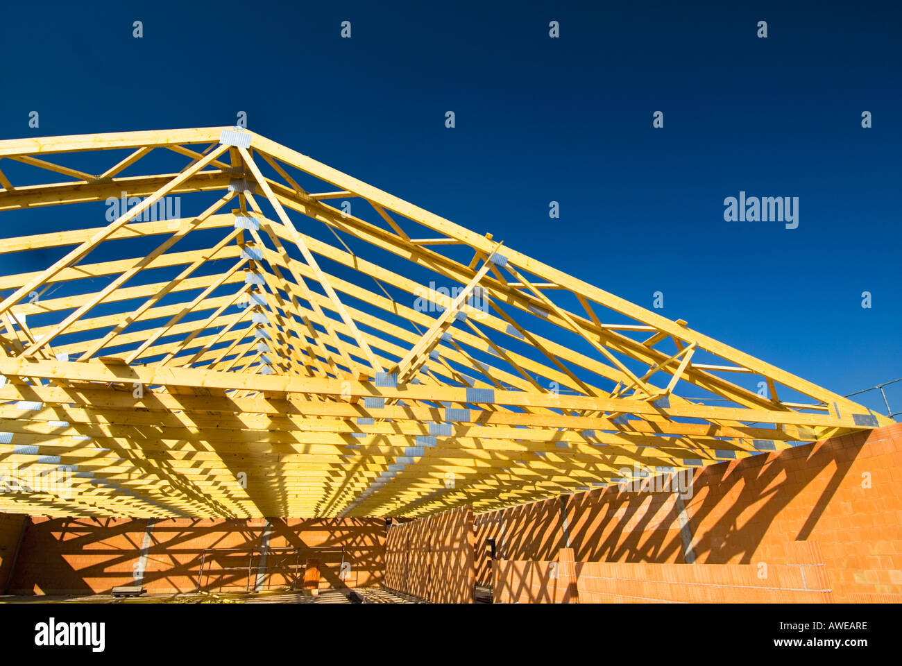 wooden roof truss timbers Construction site brick wall cement gray concrete men man at work house building new hall hangar Stock Photo
