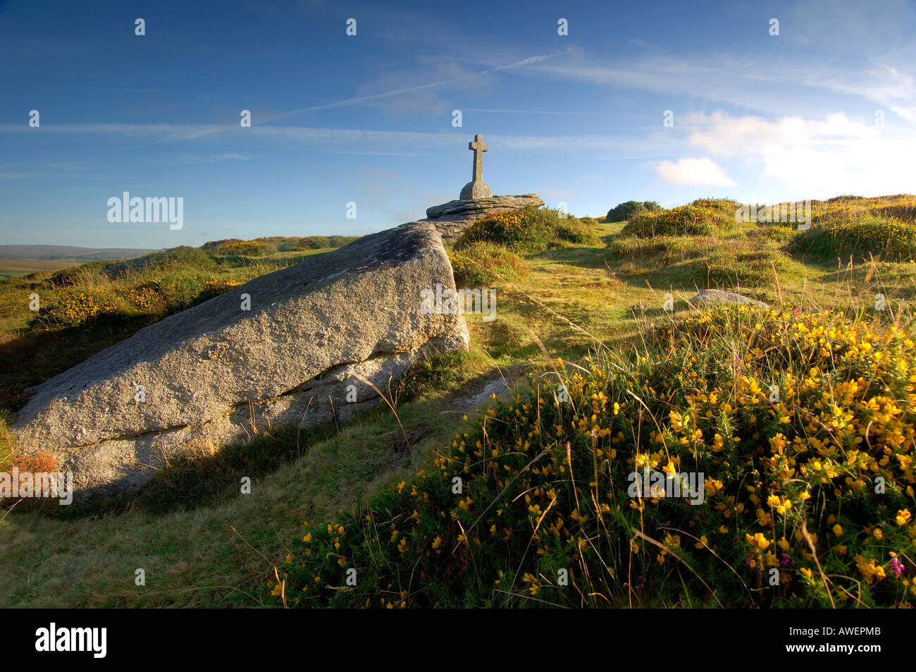 Granite cross on Dartmoor in beautiful golden summer evening light with blue sky and white clouds Stock Photo