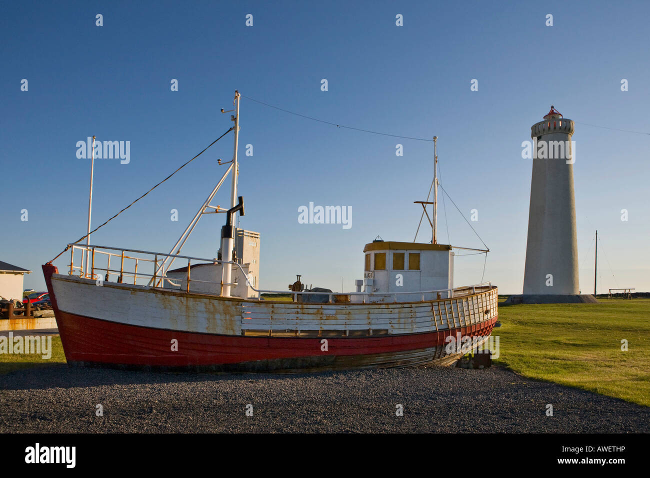 Old fishing cutter in front of Garðskagi Lighthouse, tallest in Iceland, Garður, Iceland, Atlantic Ocean Stock Photo