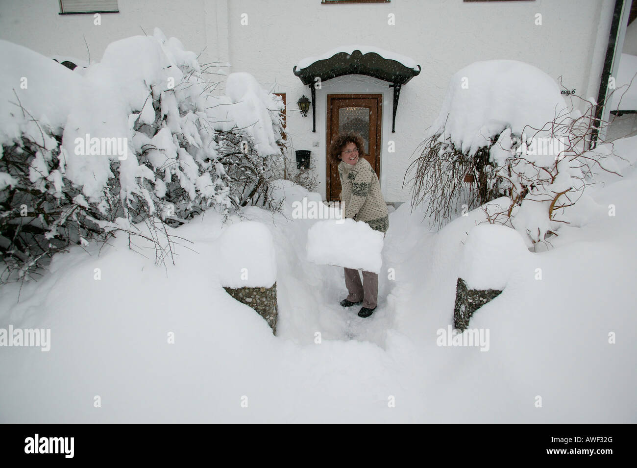Woman shovelling snow, Upper Bavaria, Bavaria, Germany, Europe Stock Photo