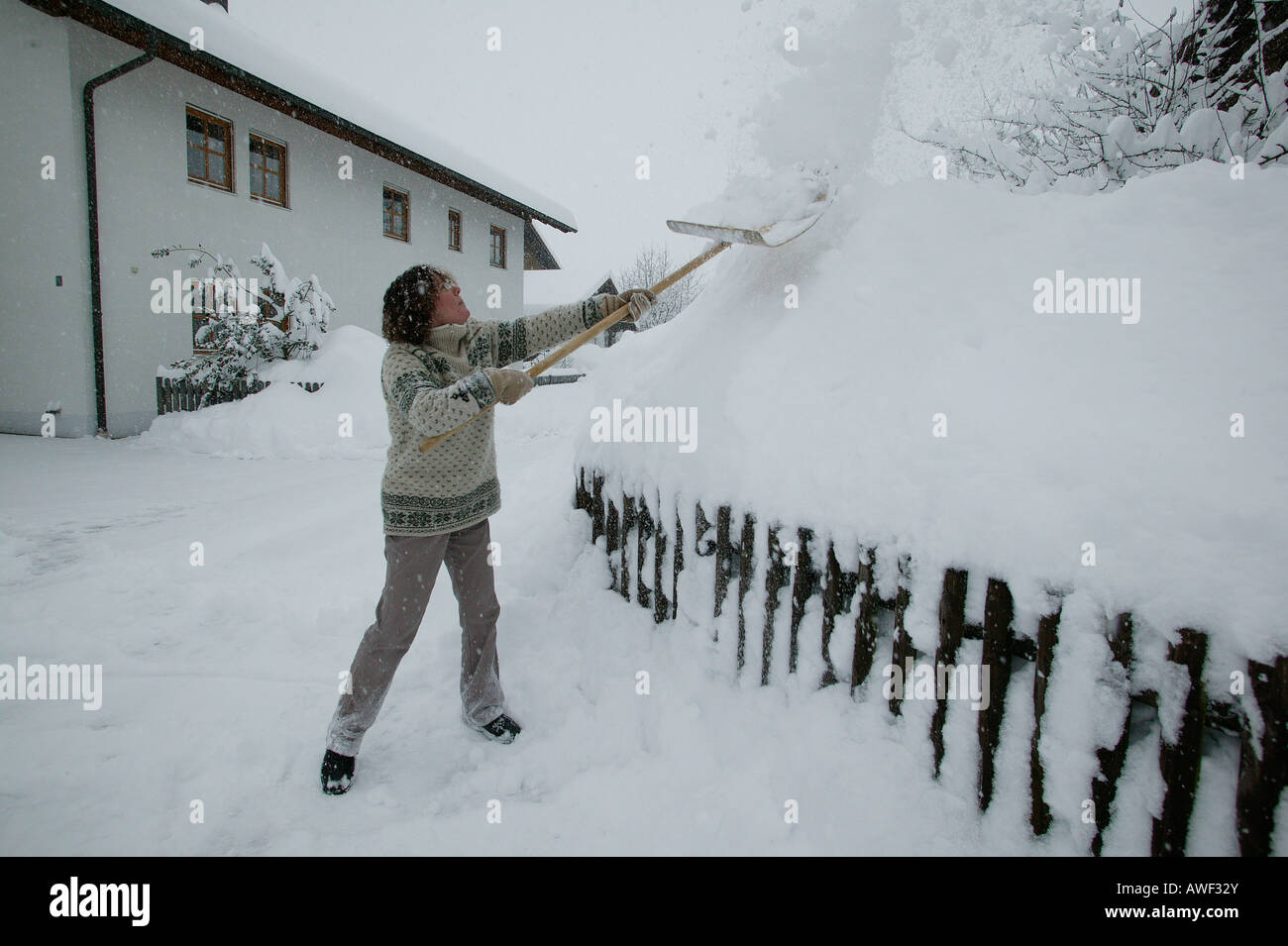 Woman shovelling snow, Upper Bavaria, Bavaria, Germany, Europe Stock Photo