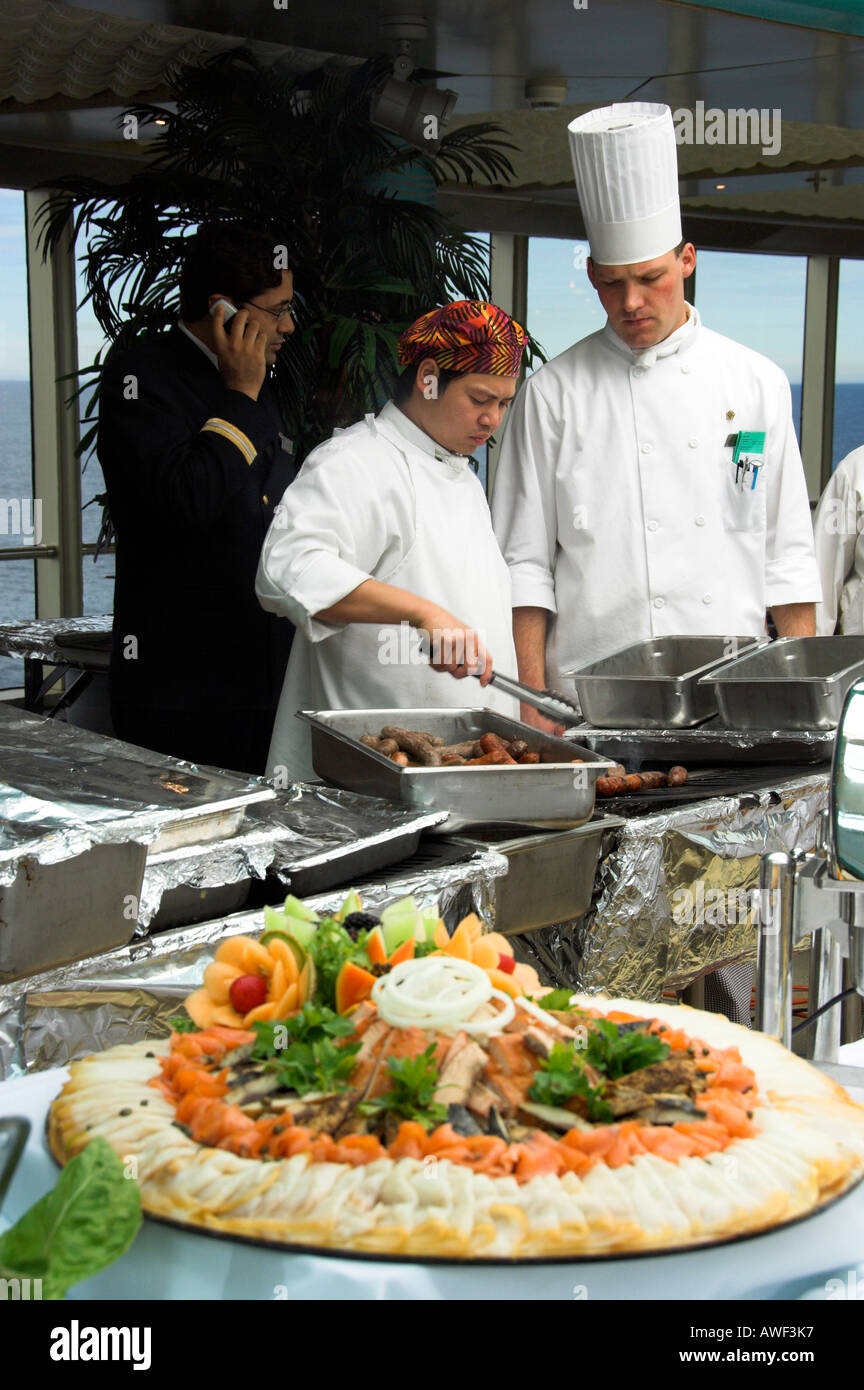 A chef on the Holland America cruise ship Zuiderdam preparing food for a large food extravaganza on deck Stock Photo