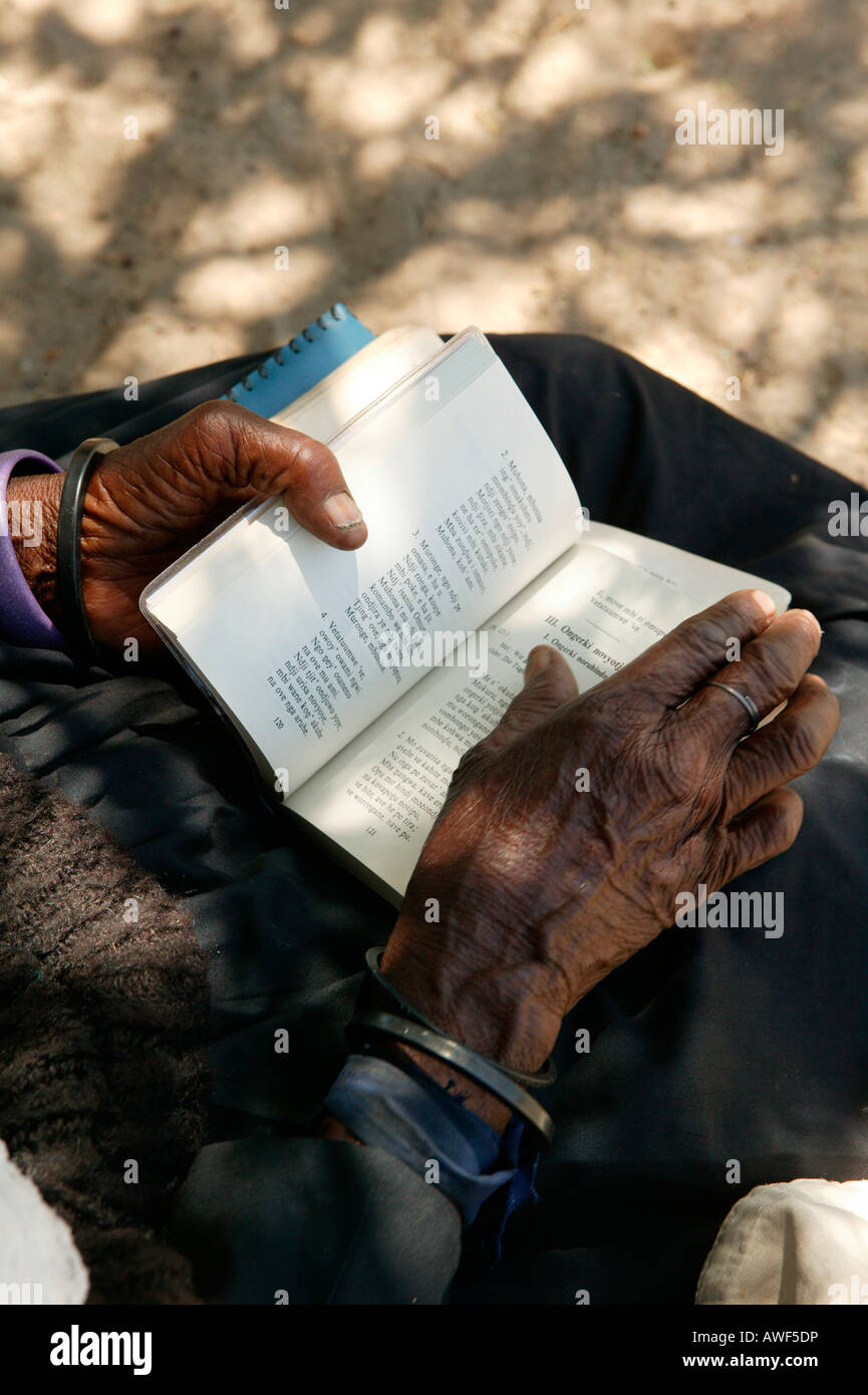Elderly woman turning the pages of a hymnal, Sehitwa, Botswana, Africa Stock Photo