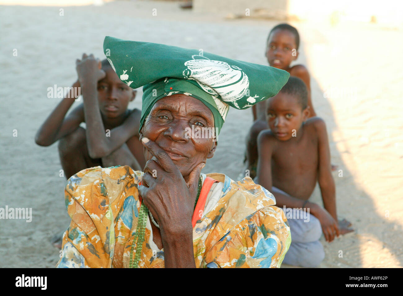 Grandmother sitting in the shade with her grandchildren, Sehitwa, Botswana, Africa Stock Photo