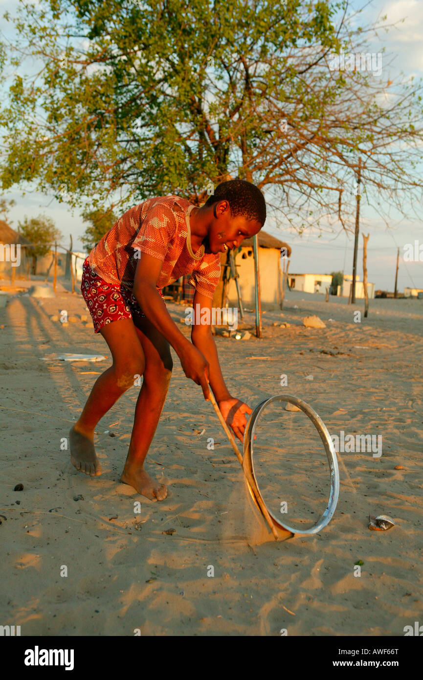 Boy playing with wheel rim on the street, Sehitwa, Botswana, Africa Stock Photo