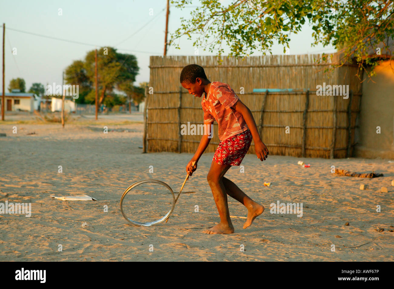 Boy playing with wheel rim on the street, Sehitwa, Botswana, Africa Stock Photo