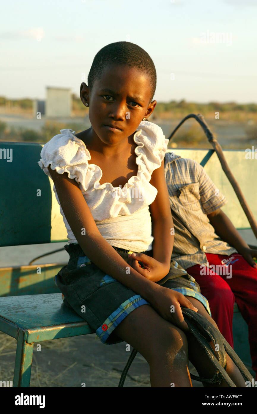 Girl sitting in box seat of a donkey cart, Sehitwa, Botswana, Africa Stock Photo