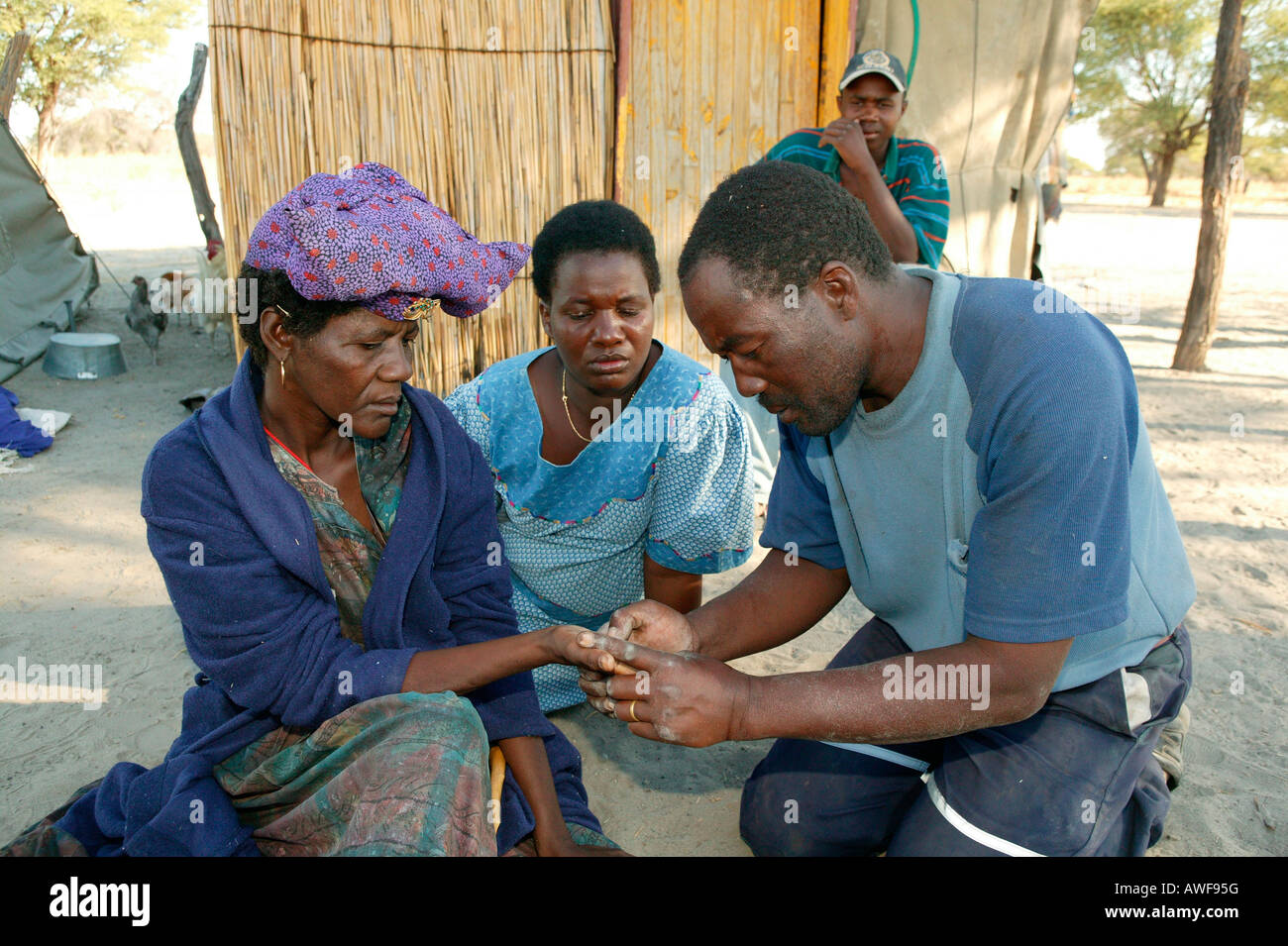 Traditional healer reading the palm of a sick patient, Sehitwa, Botswana, Africa Stock Photo