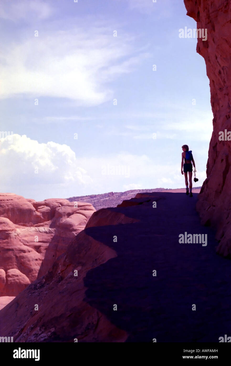 A semi-silhouetted hiker on an elevated trail to Delicate Arch. No doubt he's appreciating being shaded from the summer sun. Stock Photo