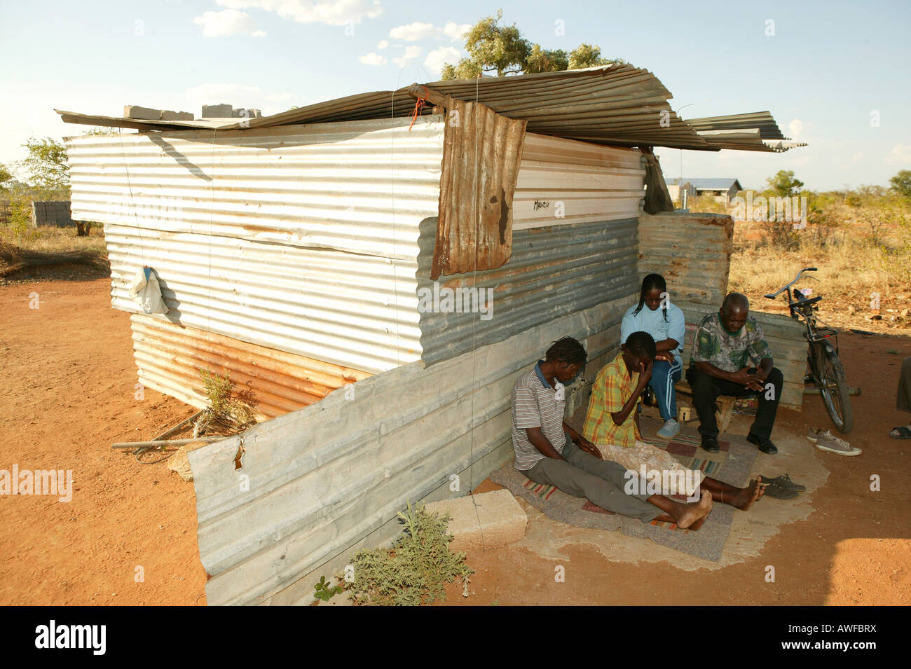 HIV/AIDS infected couple in front of their corrugated metal hut being