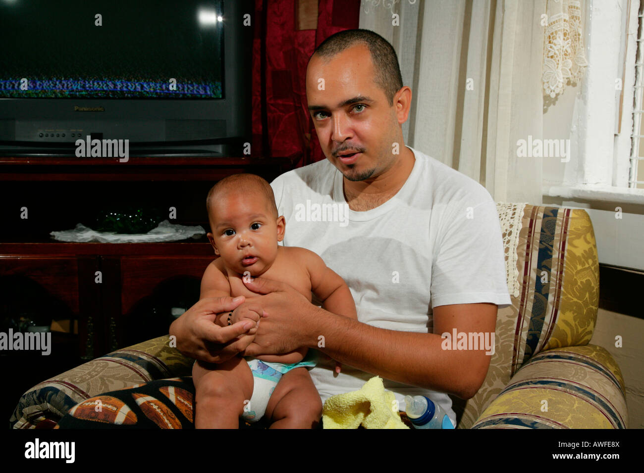 Father holding infant on his lap, Georgetown, Guyana, South America Stock Photo