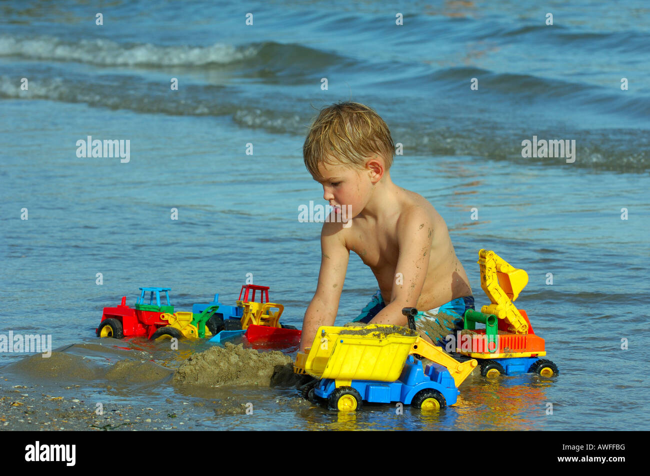 Boy sitting on the beach playing, Caorle, Veneto, Italy Stock Photo