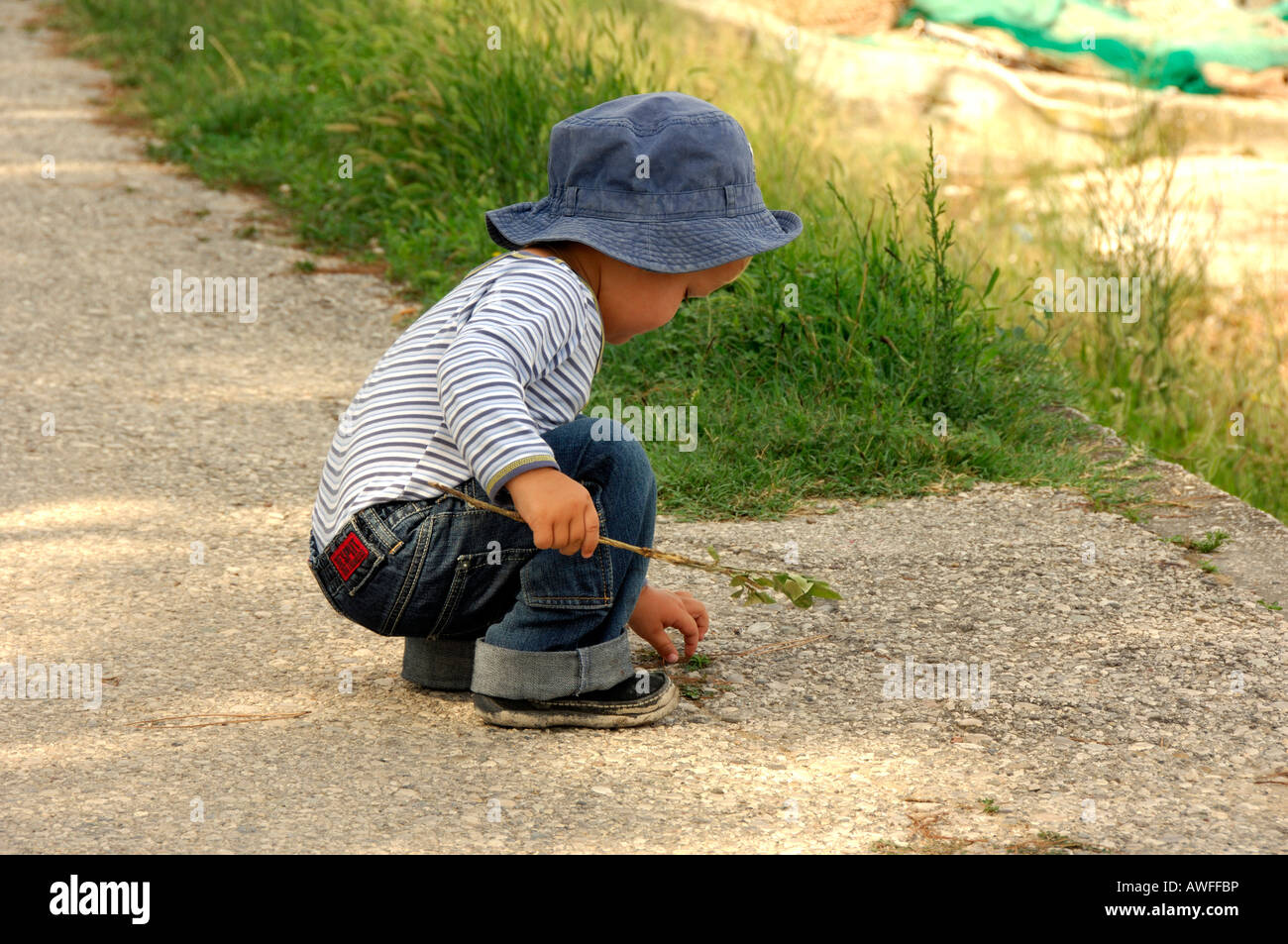 Little boy picking up something from the ground, Caorle, Veneto, Italy Stock Photo