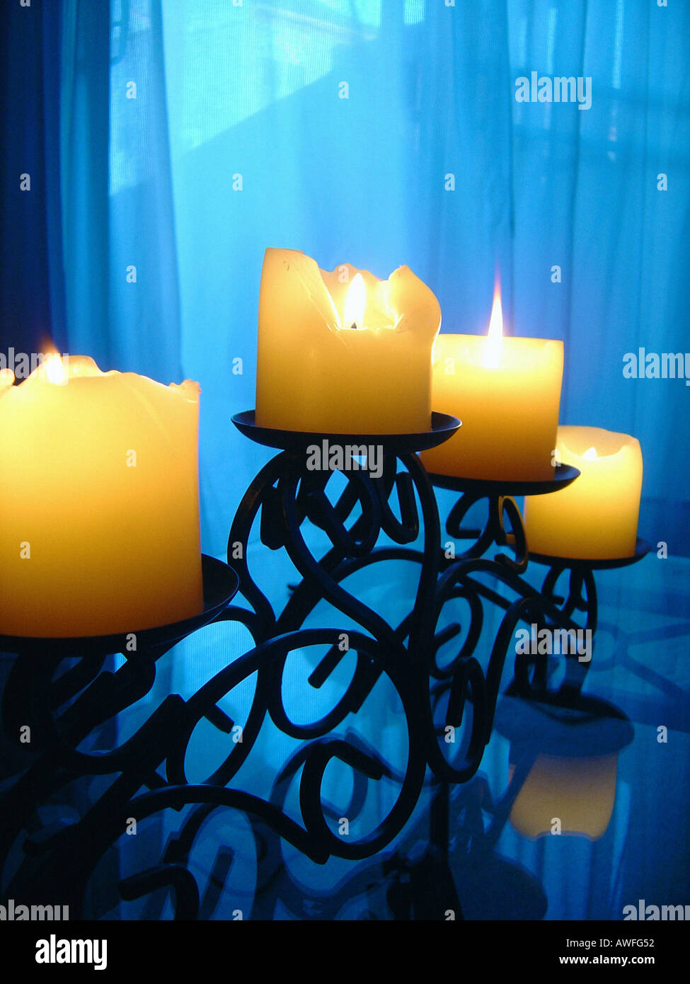 Four 4 Candles in a Cast Iron Candelabra on a Glass Table Copy Space Stock Photo