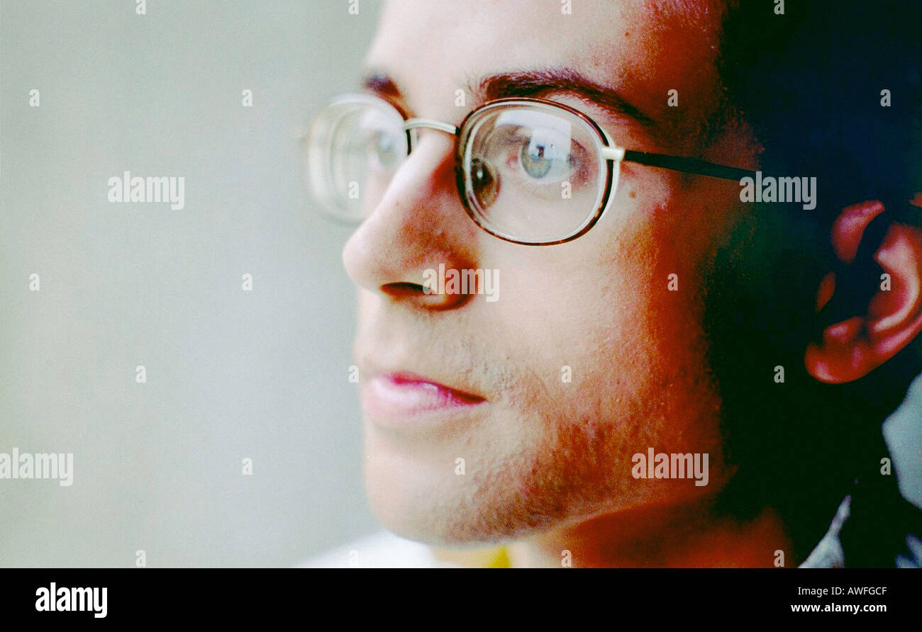Tightly Cropped Closeup Portrait of a Young Man in a White Sweater He Has Curly Hair and is Wearing Eyeglasses Copy Space Stock Photo