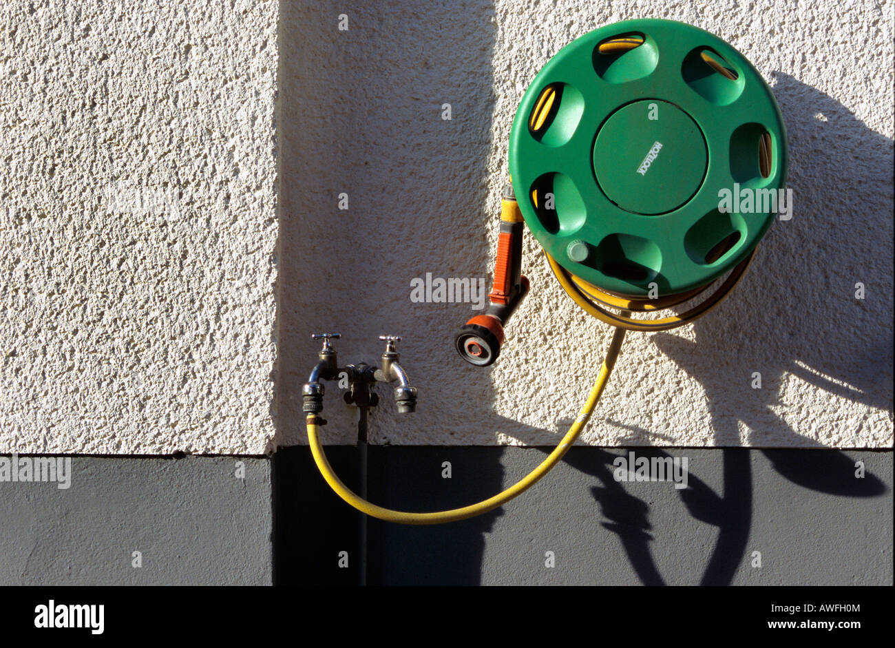 Water tap, rolled garden hose Stock Photo