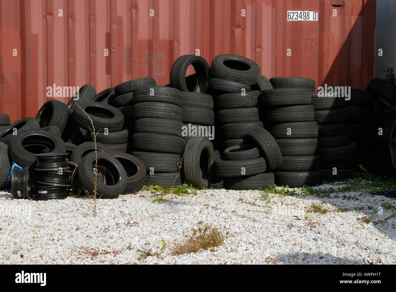 Old tires stacked in front of a shipping container Stock Photo