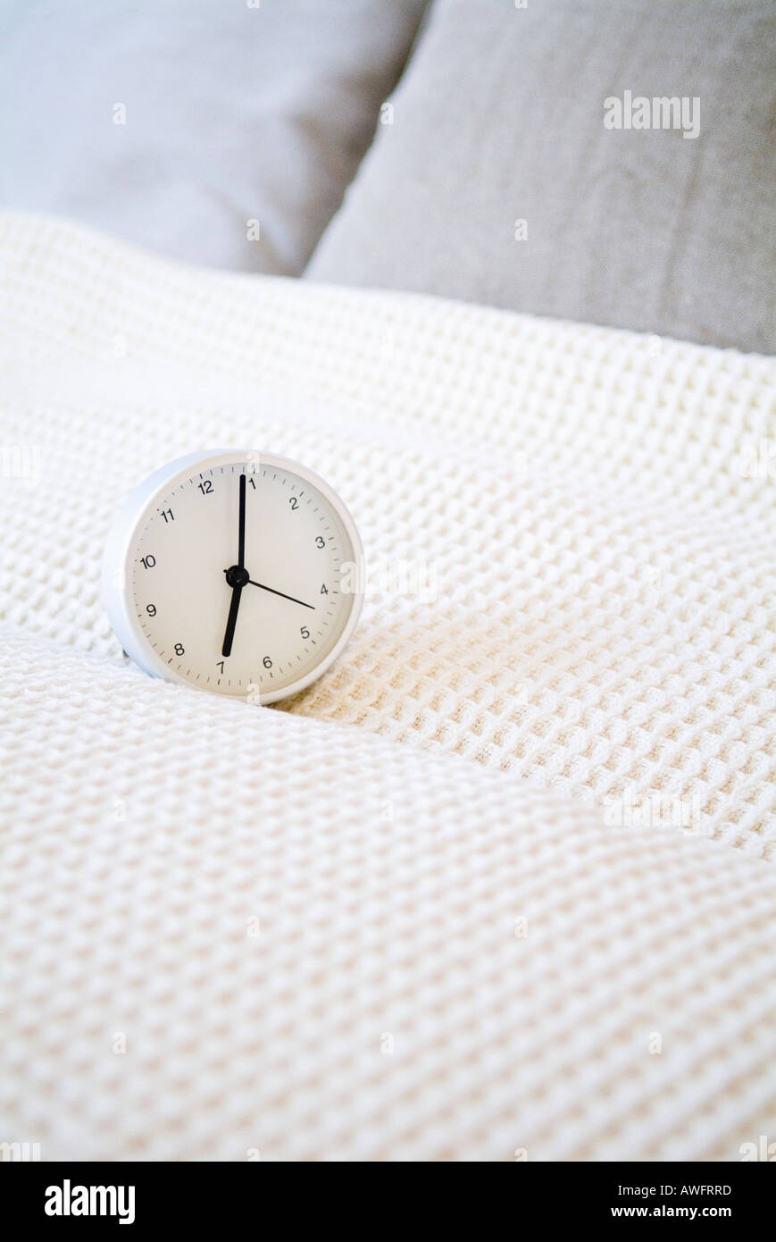 Alarm clock on bed Stock Photo