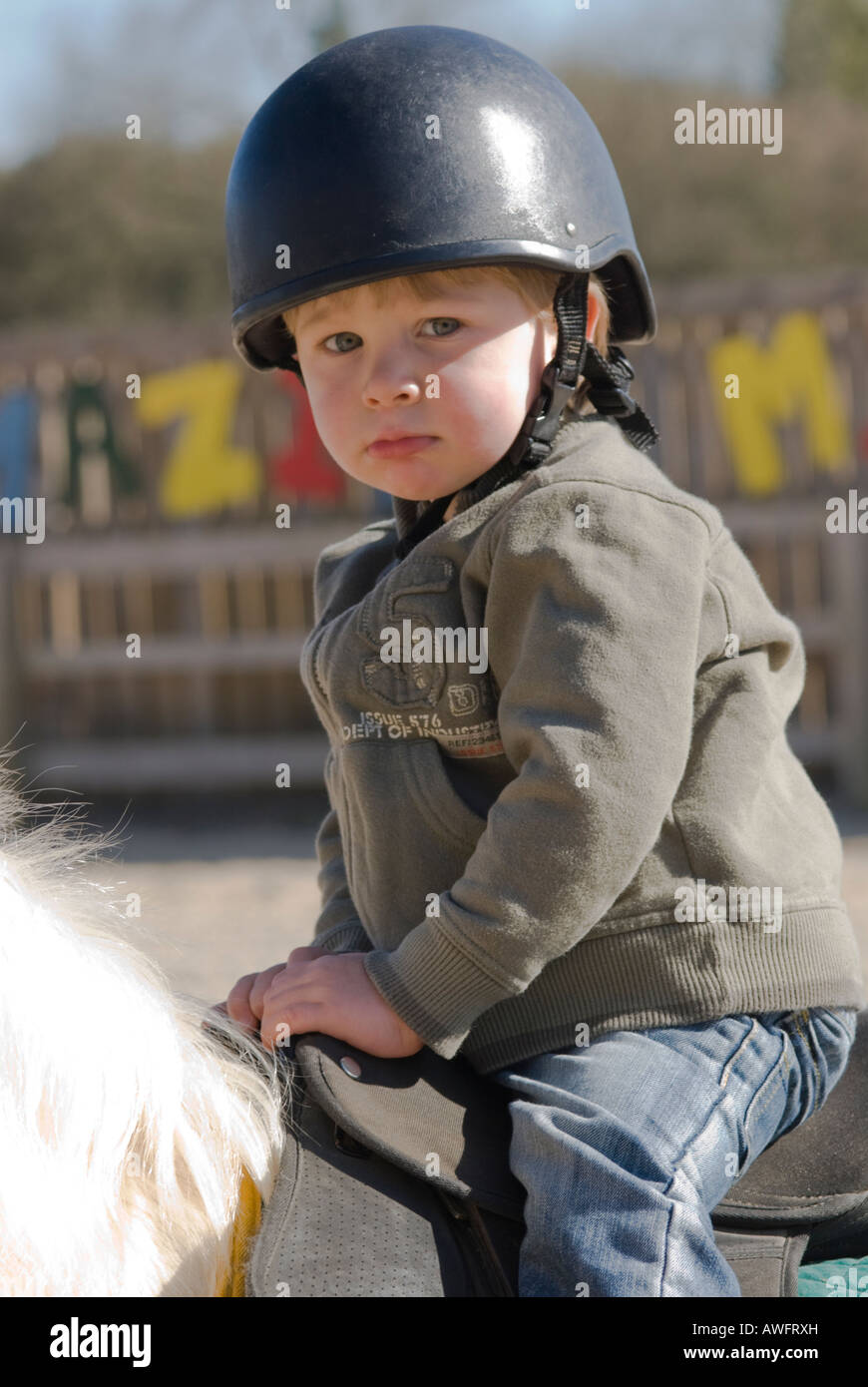 boy two years old having his first ride on a horse wearing safety