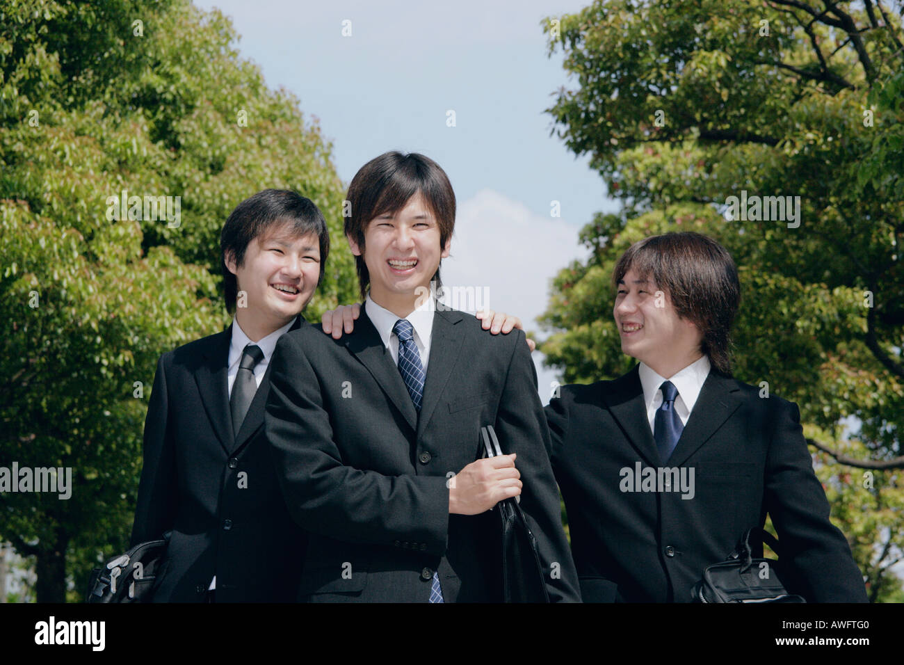 Three young men in suit smiling Stock Photo - Alamy