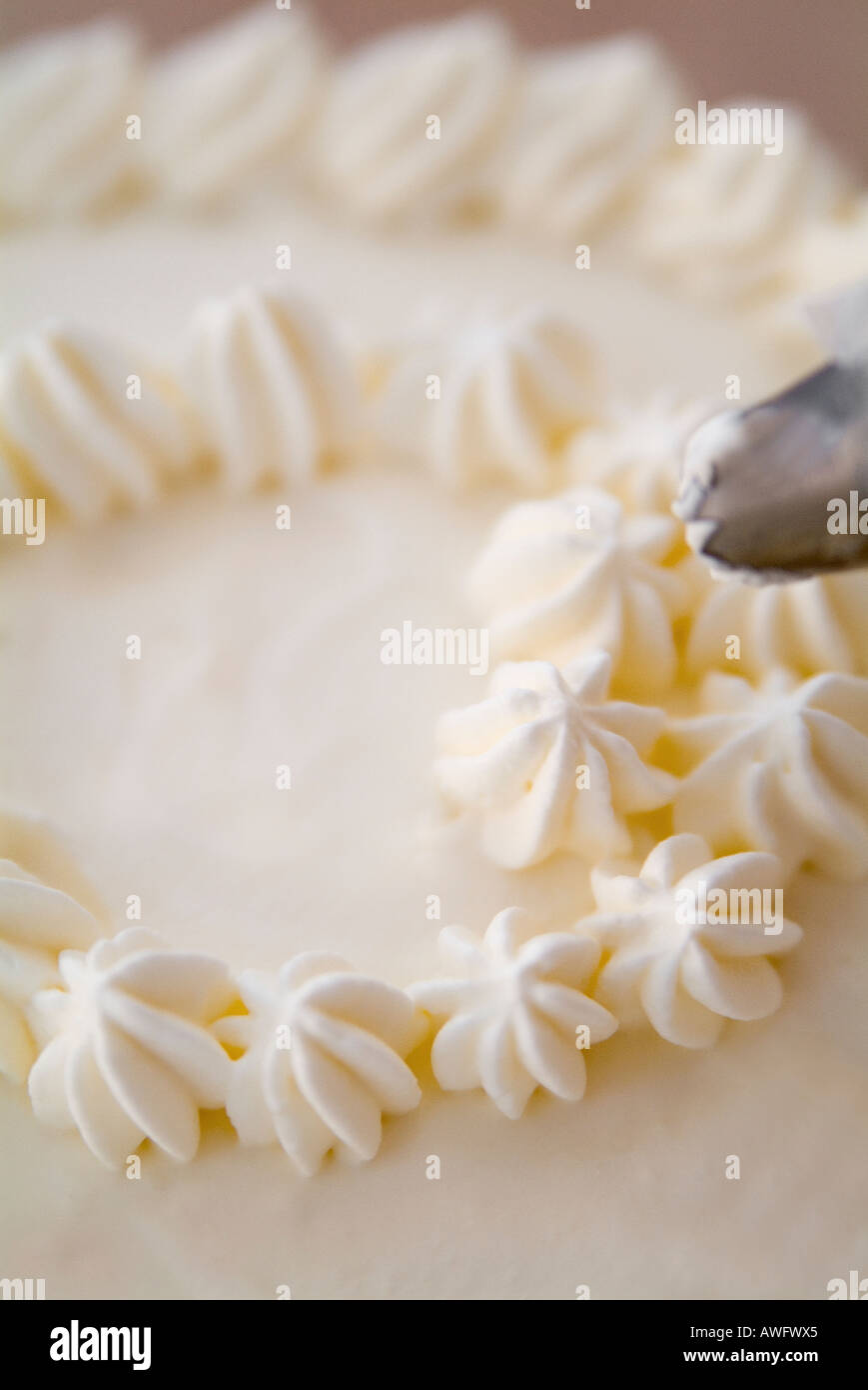 Decorating a cake with whipped cream Stock Photo Alamy