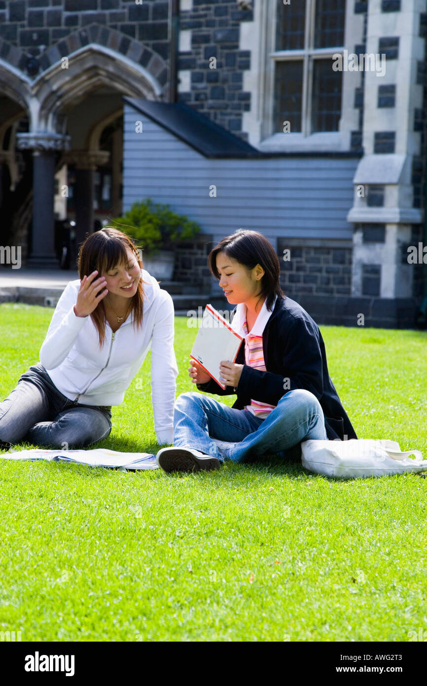 Two young women sitting on lawn Stock Photo - Alamy