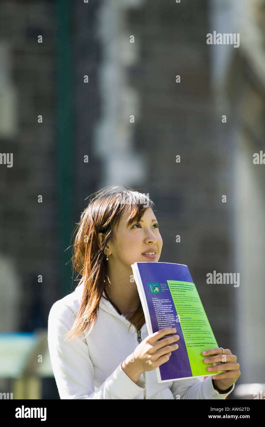 Young woman looking away with textbook Stock Photo