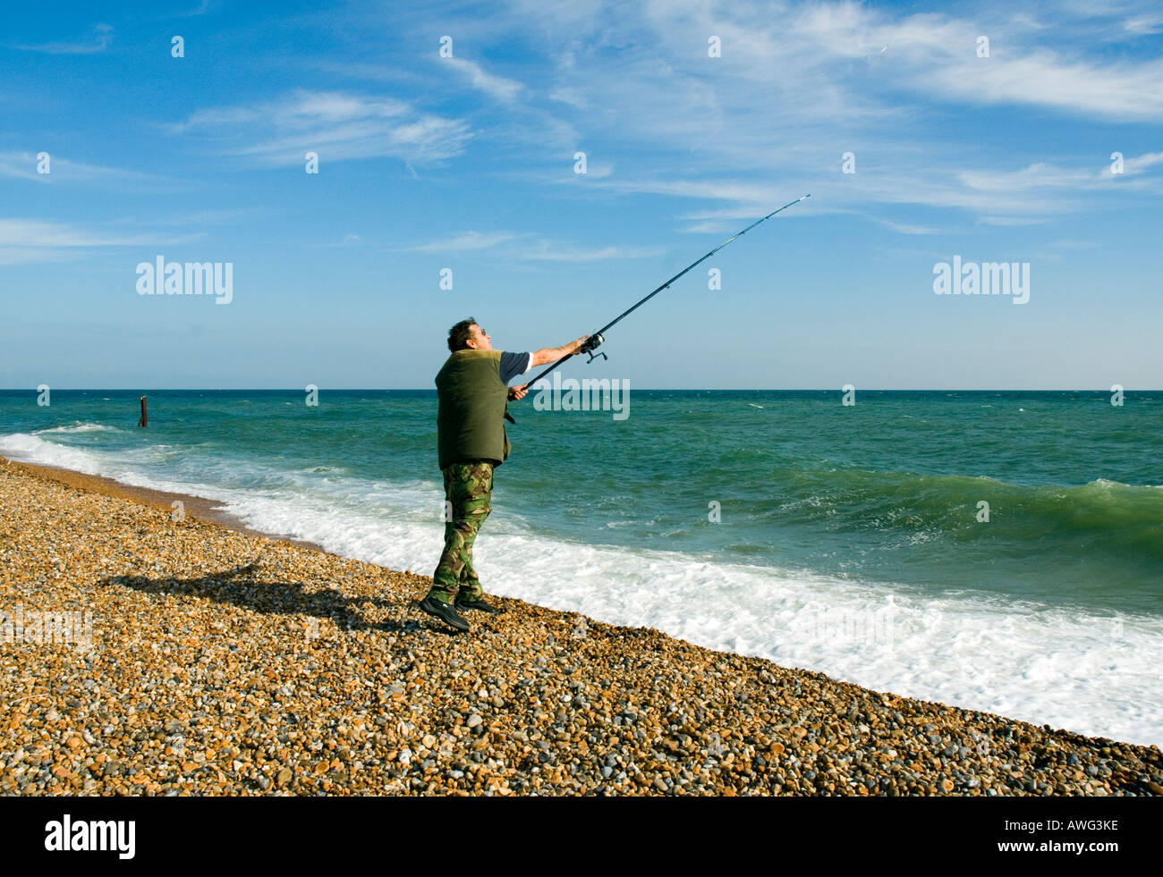 Man casting surf fishing Hastings beach East Sussex England Britain UK