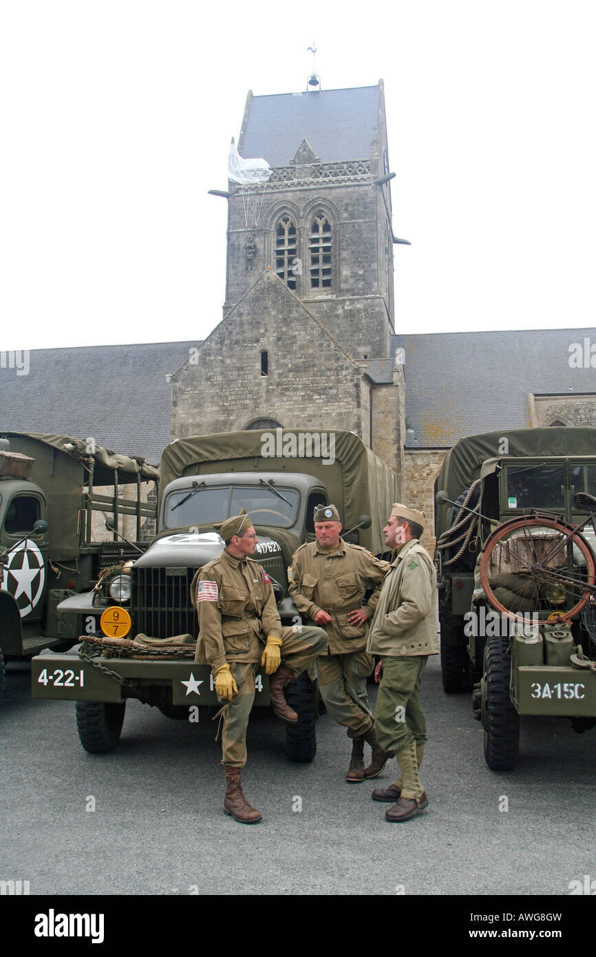 US Army WW2 Re-enactors St Mere Eglise Normandy France beneath the model of paratrooper John Steele hanging from the church Stock Photo
